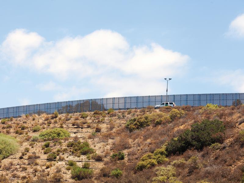 Axis' outdoor border patrol fence in daylight. Car driving by.